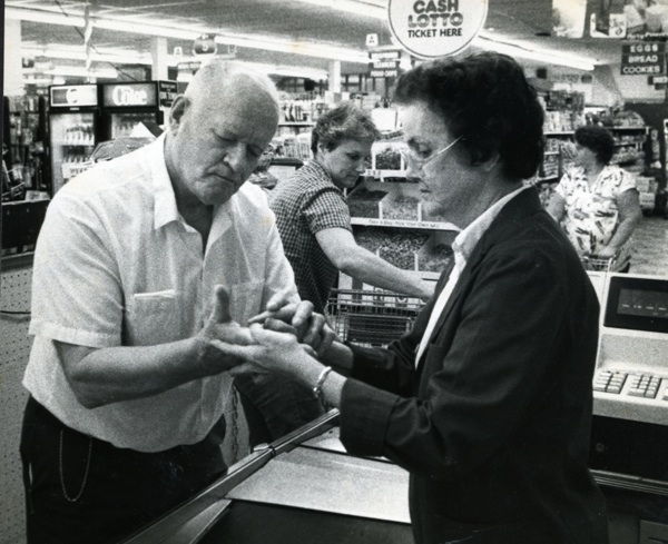 Teddy handles the household finances including having the grocery store cashier use her finger to write the total in his hand. (Copyright by John S. Stewart/LEFTeyeSTORIES.com)