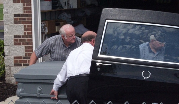Funeral home personnel and members of the Gotti entourage load an empty casket into a hearse as a decoy for the media who hoped to photograph it being loaded onto a plane for the trip to New York (Photo Copyright by John S. Stewart/LEFTeyeSTORIES.com)